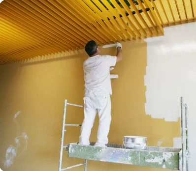 Pintor en reus pintando una casa color amarillo